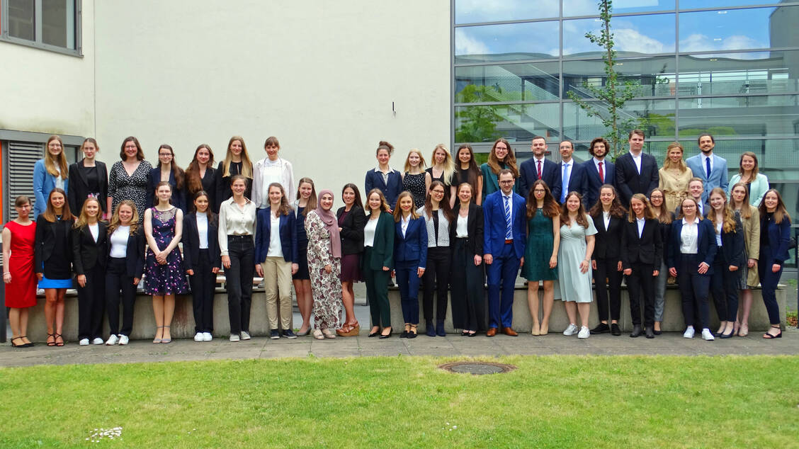 Das aktuelle Pharmazie-Abschlusssemester steht vor dem Pharma-Campus der WWU Münster neben einem von der Fachschaft Pharmazie in Erinnerung an die »Coronasemester« gepflanzten Ginkgobaum. / Foto: WWU-Münster