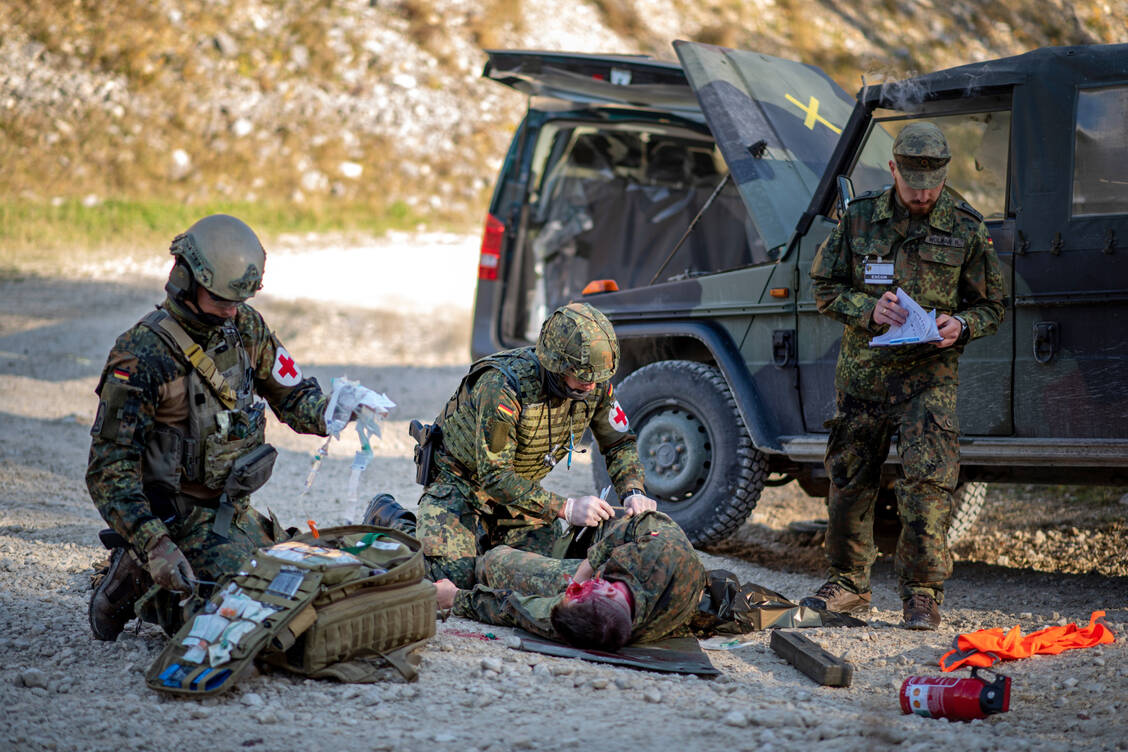 Sanitätskräfte versorgen unter Beobachtung des Fallmanagers einen verwundeten Soldaten während der Übung Donau-Samariter 2021 des Sanitätsregiments 3 in Dornstadt. Die Bundeswehrkrankenhausapotheken statten auch die Einsatzersthelfer Alpha aus. / © Bundeswehr/Patrick Grüterich