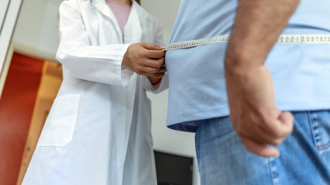 Bei einer Adipositasdiagnostik werden unter anderem der Taillen- und der Hüftumfang von Patienten gemessen. / © Getty Images/Jelena Stanojkovic