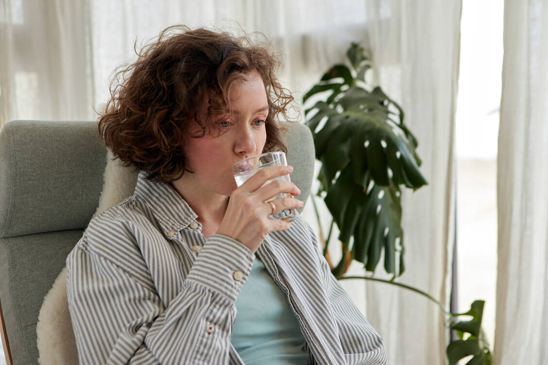 Ein Glas Wasser in kleinen Schlucken zu trinken, kann gegen Schluckauf helfen. / © Getty Images/Ekaterina Demidova