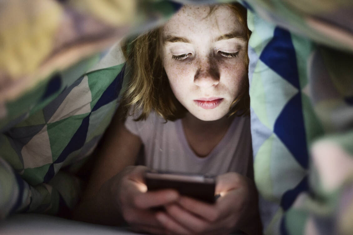 Um eine Abhängigkeit zu vermeiden, sollten Kinder und Jugendliche kein Smartphone zum Einschlafen mit ins Bett  bekommen.  / Foto: Getty Images/Westend61
