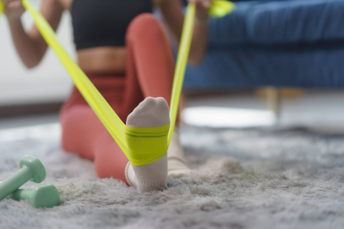 Ob mit Hanteln, Gummibändern und lediglich dem eigenen Körpergewicht – auch Zuhause lassen sich Muskeln aufbauen. Wichtig ist die Beständigkeit. / © Adobe Stock/Crystal