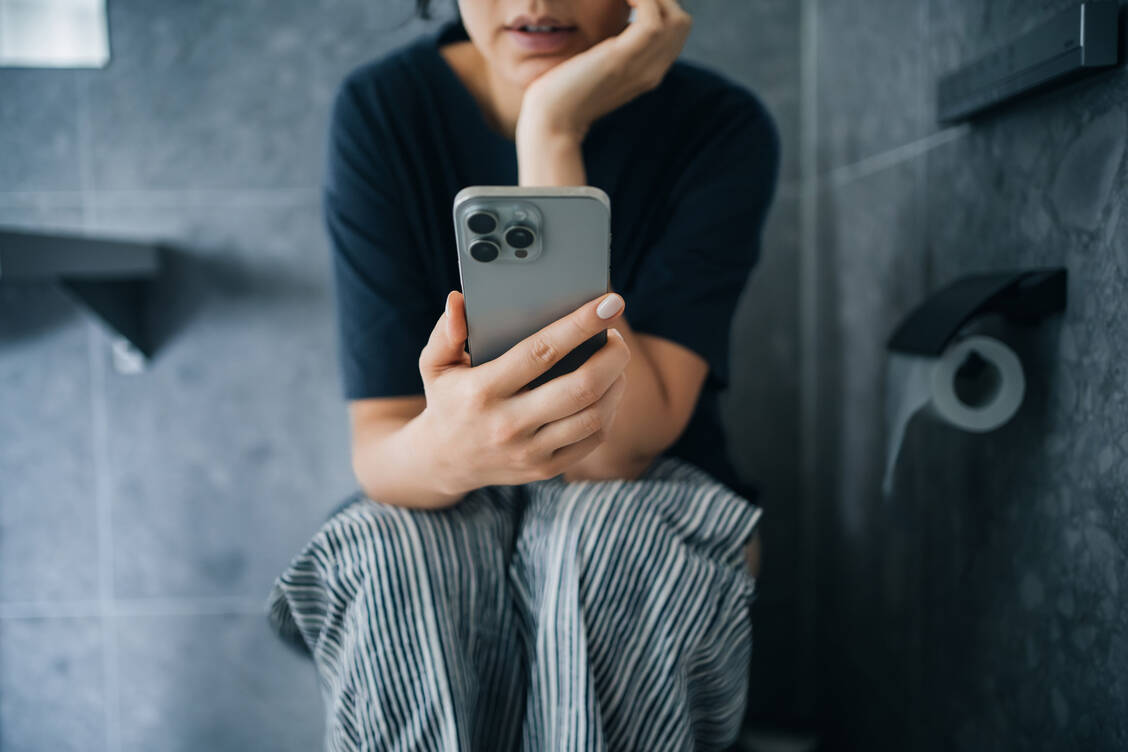Langes Sitzen ist ein Risikofaktor für Hämorrhoiden – durch die Handynutzung verlängert sich die Sitzzeit.  / © Getty Images/Yiu Yu Hoi