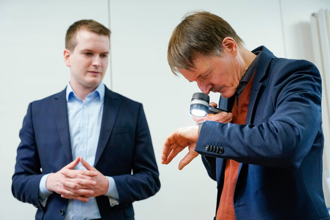 Bei einem Besuch am Deutschen Krebsforschungszentrum demonstriert Titus Brinker Gesundheitsminister Professor Karl Lauterbach (SPD) das KI-Dermatoskop. / Foto: DKFZ/Uwe Anspach