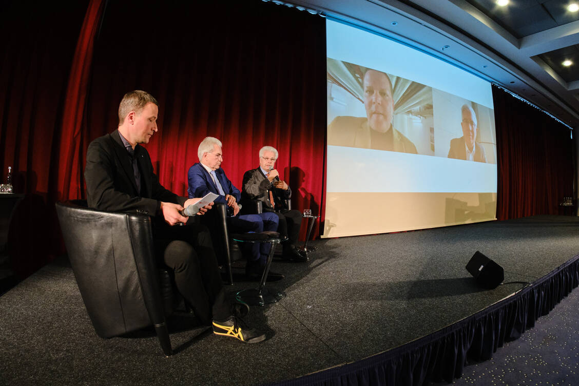 Bei der von PZ-Chefredakteur Alexander Müller (l.) moderierten Runde äußerten sich die (digital zugeschalteten) gesundheitspolitischen Sprecher von Union, Tino Sorge, und FDP, Andrew Ullmann, zu Apothekenthemen. BAK-Präsident Thomas Benkert (rechts auf der Bühne) und DAV-Chef Hans-Peter Hubmann betonten die Notwendigkeit von mehr Geld im Apothekensystem. / Foto: ABDA/André Wagenzik