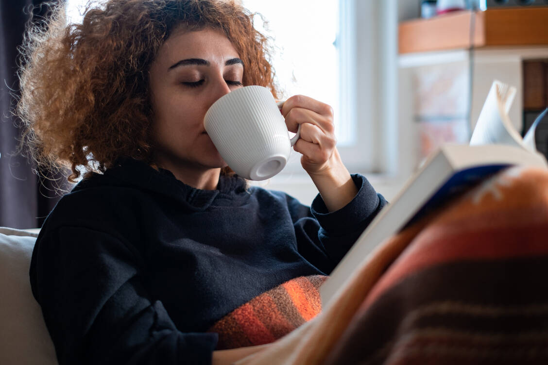 Entspanntes Lesen auf dem Sofa statt Coffee to go: Entspannung und Sparsamkeit lassen sich prima kombinieren. / Foto: Getty Images/mahiruysal