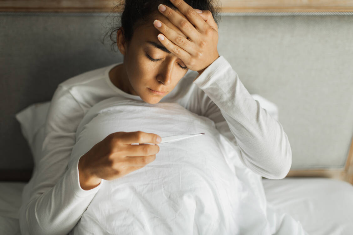 Plötzliches hohes Fieber, begleitet von starken Glieder- und Muskelschmerzen, deutet eher auf eine echte Grippe als eine Erkältung hin. Typisch für letztere ist Halskratzen als erstes Symptom. / © Getty Images/Oleg Breslavtsev