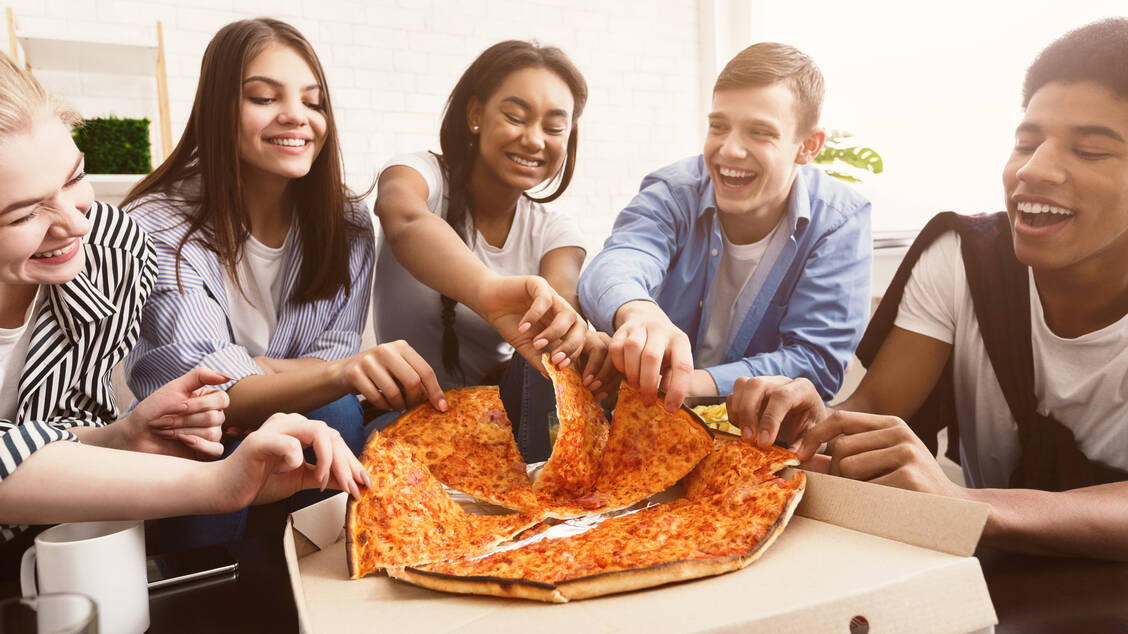 Gemeinsam schmeckt die Pizza doppelt so gut. Jedoch essen viele Jugendliche zu viel fettiges und salzhaltiges Fastfood sowie Süßigkeiten.  / Foto: Adobe Stock/Prostock-studio