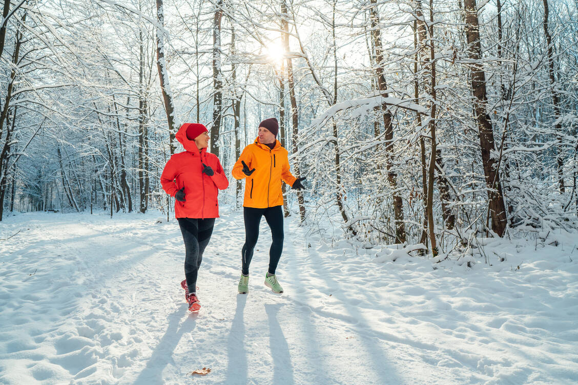 Dieses Duo macht es richtig: Im Winter sollte die Laufbekleidung stets lang sein. Auch Mütze und Handschuhe empfehlen sich bei kalten Temperaturen. / © Getty Images/Solovyova