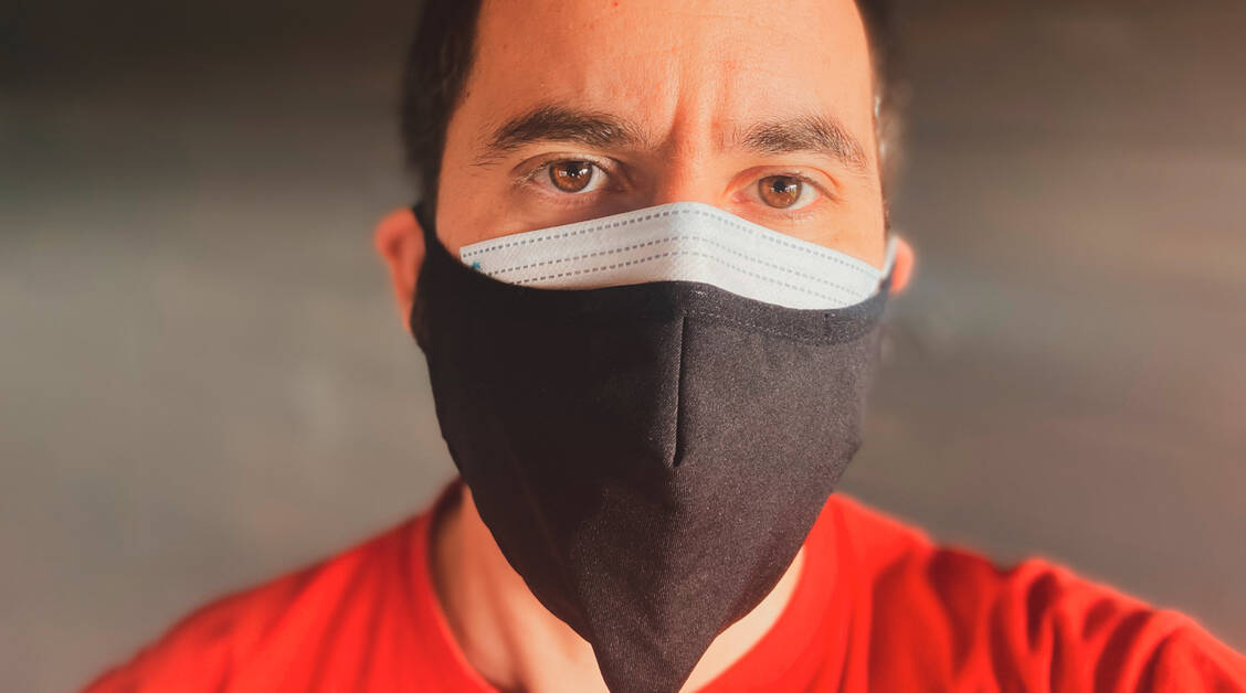 Eine Stoffmaske über dem Mund-Nasen-Schutz soll die Schutzwirkung erhöhen.  / Foto: Adobe Stock / bacothelock