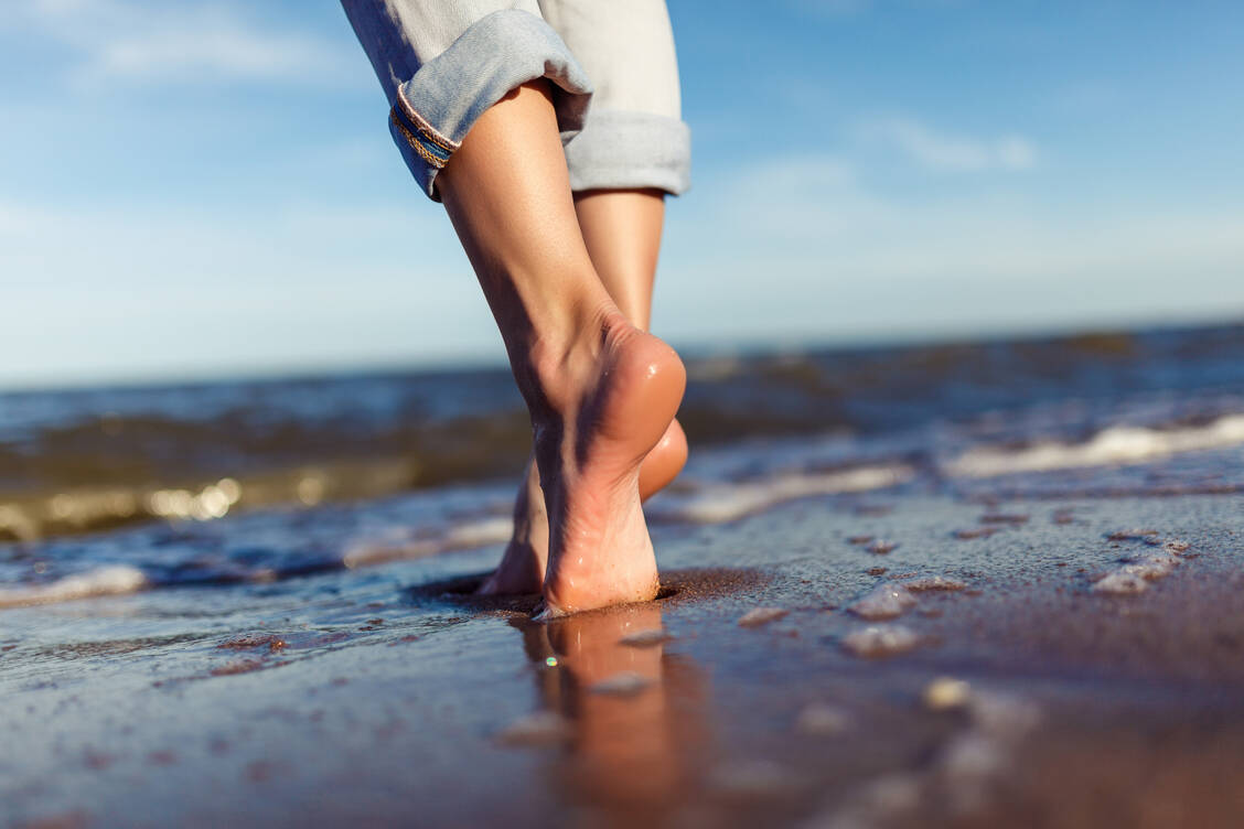 Am Strand barfuß zu laufen, kann eine positive Wirkung auf Knie-, Hüft- und Rückenprobleme haben. / Foto: Adobe Stock/toxicoz