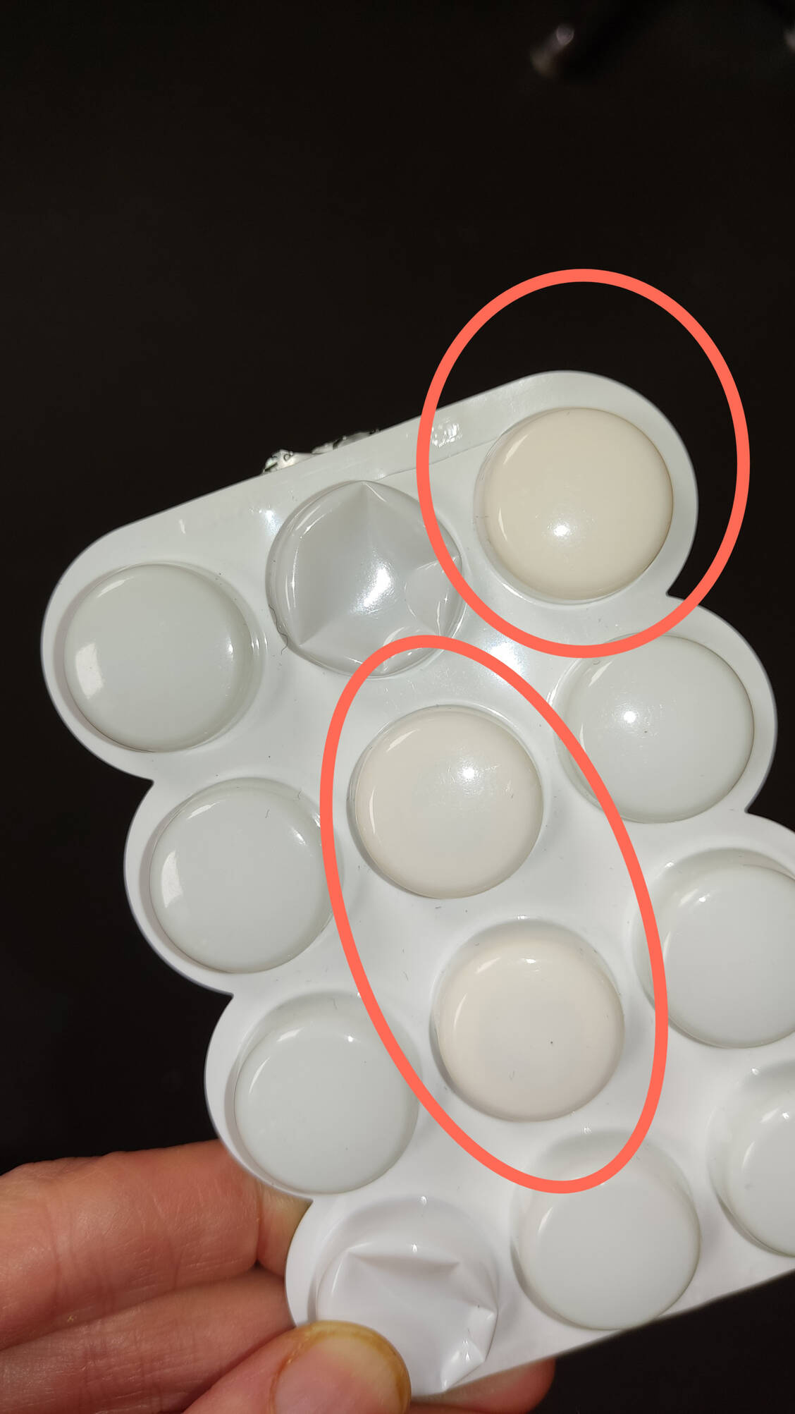 Durch den Blister durchscheinend sind farblich veränderte Lutschtabletten (rot eingekreist) erkennbar. / © AMK