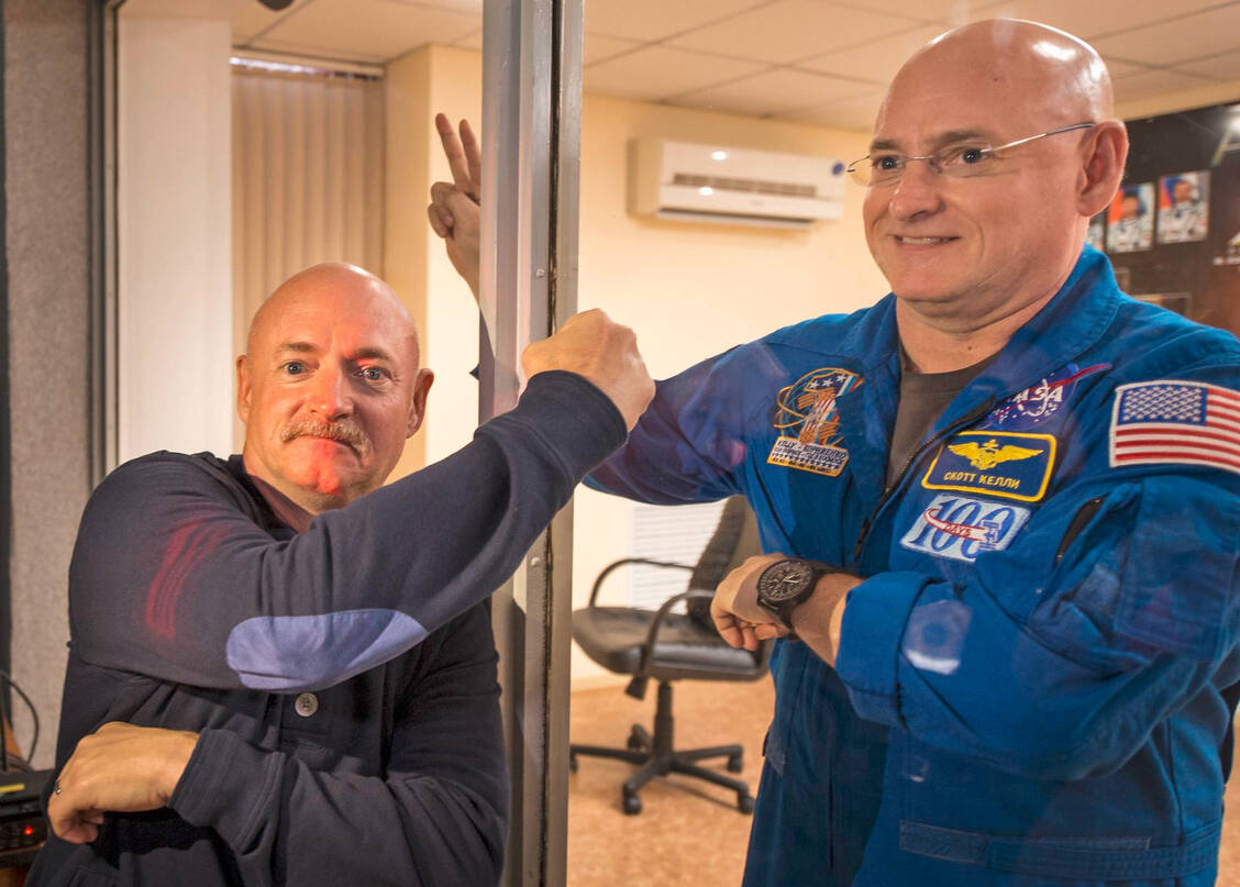 Mark Kelly (links) und sein Zwillingsbruder Scott scherzen durch die Glasscheibe der Quarantäne. 2015 flog Scott für fast ein Jahr ins All. Währenddessen nahm Mark, selbst ein erfahrener Space-Shuttle-Astronaut, auf der Erde an vergleichenden biomedizinischen Studien teil. / Foto: NASA/Bill Ingalls