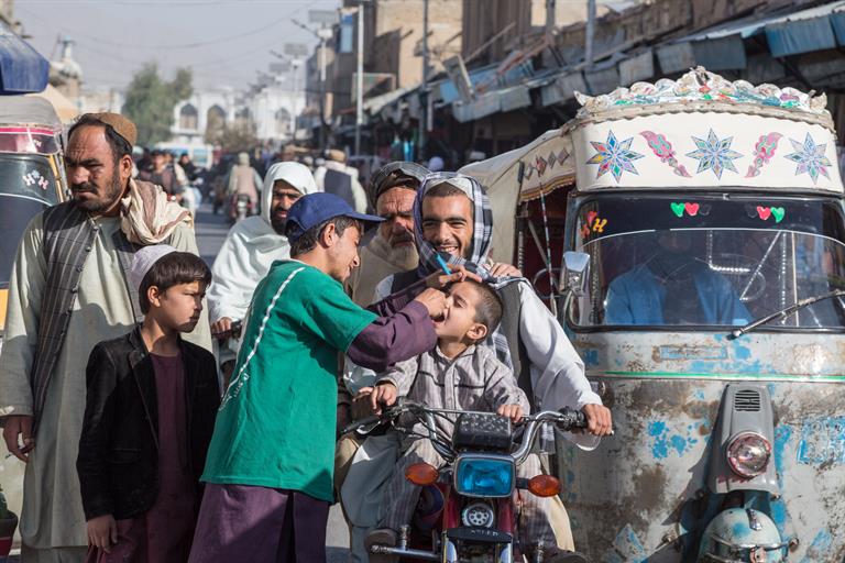 Ein Freiwilliger gibt einem afghanischen Jungen auf der Straße die orale Polio-Vakzine. Foto: WHO/G. Elham